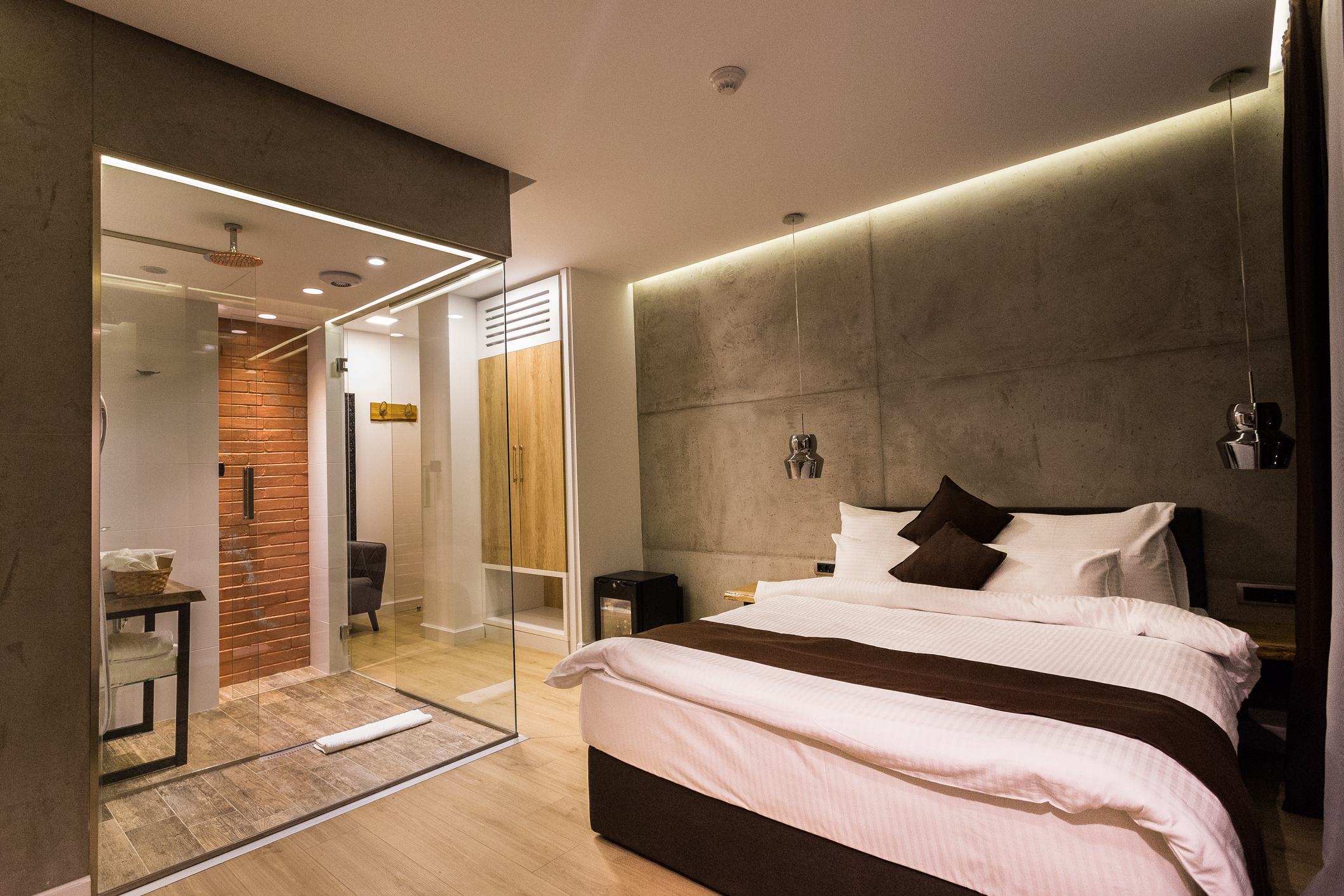 Modern hotel en suite bathroom. Stainless steel washing baisin and glass shower cabin.